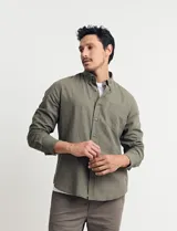 Camisa de manga larga confeccionada en una mezcla de algodón y lino, con cuello abotonado, bolsillo frontal en el pecho y cierre de botones.