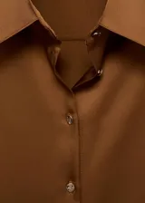 Camisa de poliéster con acabado satinado en color tostado, cuello camisero, manga larga con puños anchos abotonados y cierre frontal de botones.