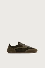 Zapatilla de cordones confeccionada en piel con acabado de serraje en tonos marrones. Presenta un diseño de perfil bajo con suela ultrafina a contraste y detalle de pespuntes decorativos.