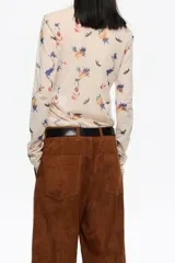 Camiseta de manga larga, corte ajustado, confeccionada en tul de poliamida con estampado de insectos y motivos florales en tonos azules, naranjas y verdes sobre fondo beige claro. Presenta cuello caja y puños con acabado en crudo.