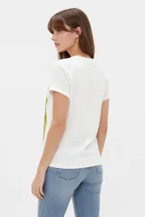 Remera de algodón color beige, de manga corta con vuelta, cuello redondo y estampa frontal de flores con lazo en tonos azules y celestes.