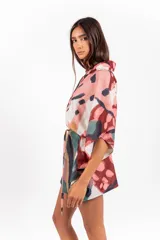 Vestido camisero oversize de tela calada con estampado abstracto multicolor, cuello camisero, mangas anchas y lazo ajustable en la cintura confeccionado en la misma tela.