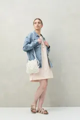 Vestido corto color rosa pálido, de algodón con bordado floral en relieve, escote redondo con abotonadura frontal y mangas amplias.