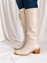 Bota de caña alta color suela, confeccionada en cuero napa, con diseño de caña caída y ajuste mediante cordones en la parte superior. Presenta un taco cuadrado foliado de 4,5 cm y suela de goma antideslizante.