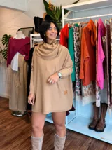 Polerón oversize de tejido de punto color naranja, con cuello alto tipo polera, mangas largas con puños acanalados y bolsillos laterales. Presenta un detalle de etiqueta de cuero en la parte inferior.