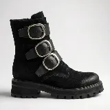 Bota de caña media en gamuza negra, con suela track dentada y tres correas horizontales con hebillas metálicas plateadas.