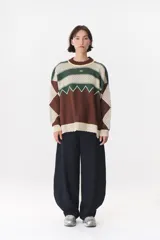 Buzo de tejido de punto con diseño geométrico y combinación de colores en contraste. Presenta cuello redondo, mangas largas y corte oversized.