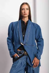 Blazer de denim azul con corte a la cintura, cuello solapa y detalle de cierre con botón de guampa.