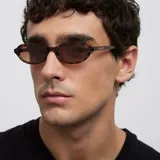 Lentes de sol con montura ovalada de diseño carey y cristales polarizados en color marrón.
