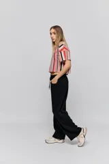 Babucha de calce relajado color negro, con cintura elastizada, cordón de ajuste y bolsillos laterales. Presenta un diseño de pernera amplia y cómoda.