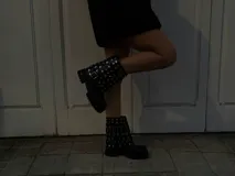 Botas cortas de cuero negro con suela track, punta redondeada y caña decorada con múltiples tachas metálicas plateadas y una hebilla lateral.