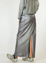 Falda midi color plateado metalizado, de corte recto con tajo en la espalda. Presenta detalles de costura que simulan bolsillos traseros.