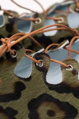 Semibotín de piel de pony con estampado animal print en tonos verde y marrón. Presenta un diseño con aberturas laterales onduladas, cierre de cordones finos y punta afilada. Cuenta con suela de cuero y cuña interna.
