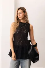 Vestido corto sin mangas de encaje negro, con escote bote y terminación de volados superpuestos.
