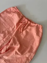 Conjunto de bikini estampado con flores y hojas en tonos rosados, amarillos y verdes. Incluye corpiño con aro y bombacha con lazos laterales.