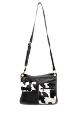 Morral bandolera de cuero negro con dos bolsillos frontales de cuero con estampado animal print de vaca.