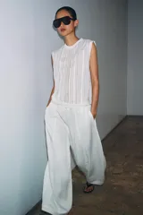 Blusa sin mangas de algodón con cuello redondo, diseño con paneles verticales bordados y detalles de encaje, cierre posterior con abertura y botón.