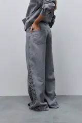 Jean wide leg de tiro alto color gris, con pierna extra ancha y recorte lateral con estampado animal print en tonos grises.