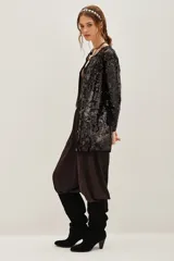 Tapado negro de corte recto completamente cubierto de lentejuelas, con mangas largas y cierre frontal. Presenta un diseño elegante y brillante ideal para eventos nocturnos.