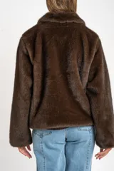 Abrigo de piel sintética en color marrón, con cuello clásico, cierre frontal con cremallera y mangas largas.