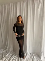 Vestido largo de encaje negro con transparencias, mangas largas y cuello redondo, acompañado de un top y un short interior a juego.