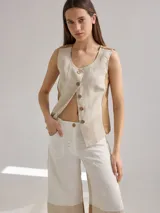 Chaleco de lino color beige con paneles laterales en tono tostado, cuello redondo y cierre frontal con botones.