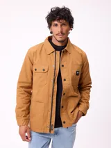 Campera estilo overshirt de gabardina color tostado, con cierre frontal de cremallera y botones a presión. Cuenta con múltiples bolsillos delanteros con solapa y etiqueta de la marca en el pecho.