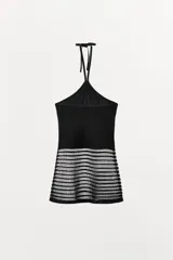 Top negro con cuello halter ajustable mediante lazo. La parte superior es opaca y ajustada, mientras que la parte inferior presenta un tejido semitransparente con franjas horizontales en relieve.