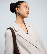 Saco largo de corte recto confeccionado en polivelour, con cuello de solapas, cierre frontal con botones y bolsillos laterales. Presenta un diseño elegante y funcional, ideal para la temporada de invierno.