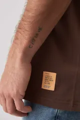 Remera marrón de manga corta, con cuello redondo y diseño holgado.