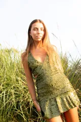 Vestido corto negro con estampado de plumas doradas, escote en V, breteles finos cruzados en la espalda, cut-outs laterales y volado en el ruedo.