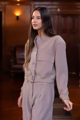 Chaqueta bomber color visón con cuello mao, cierre frontal con botones a presión, dos bolsillos de parche con solapa en el pecho, puños y cintura acanalados.