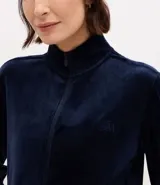 Campera deportiva de mujer confeccionada en tejido plush aterciopelado. Presenta cuello alto, cierre frontal con cremallera y puños ajustados.