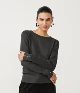 Suéter de punto color rosado, con cuello barco, mangas largas y puños con botones decorativos. El dobladillo también es acanalado.