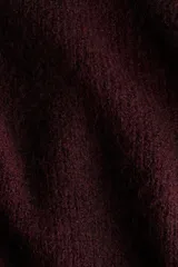 Buzo de punto acanalado con escote off-the-shoulder y detalle de nudo frontal. Presenta un diseño ajustado de manga larga y bajo recto.