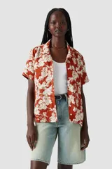 Camisa de manga corta color ladrillo con estampado de flores blancas, cuello clásico y corte recto.