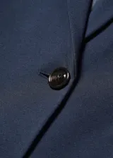 Blazer negro entallado de punto roma con solapas de muesca, hombros estructurados, abertura posterior y dos bolsillos de ribete delanteros.