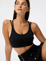 Top deportivo negro con escote redondo, doble tirante fino y sutil logo estampado en el pecho.