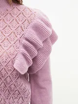 Buzo de tejido de punto calado en color lila, con cuello alto, mangas largas con puños ajustados y detalle de volados en los hombros.
