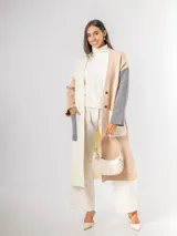 Sacón tipo tapado de corte largo, confeccionado en tejido de punto con diseño color block en tonos gris, negro y blanco. Presenta cierre frontal con botones, bolsillos laterales de parche y aberturas en los costados.