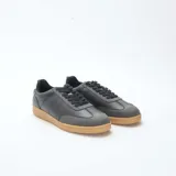 Zapatillas urbanas bajas de cuero sintético negro con puntera gris y suela marrón.