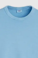 Remera celeste de manga corta, con cuello redondo y diseño holgado con aberturas laterales en el dobladillo.