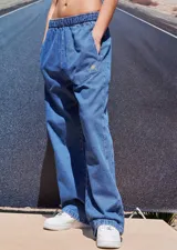 Pantalón de jean azul de corte babucha, tiro medio, con elástico en la cintura, bolsillos delanteros y logo bordado en amarillo en la pierna derecha.