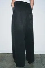 Jeans de tiro bajo con corte baggy y pierna ancha. Presenta diseño de cinco bolsillos, cierre frontal con cremallera y botón metálico, y cintura con trabillas para cinturón.