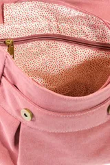 Mochila de lona estilo vintage con solapa frontal, bolsillos laterales y correas ajustables. Presenta detalles en cuero sintético y un parche decorativo en la parte superior.