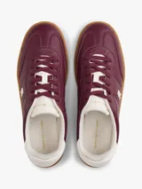 Zapatillas de corte bajo confeccionadas en piel napa brillante color bordó, con suela de goma color caramelo. Presentan insignia metálica del monograma TH en el lateral y detalle en blanco en el talón.