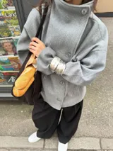 Chaqueta de paño color marrón oscuro, con diseño de doble botonadura frontal y cuello alto estructurado. Presenta mangas largas y un corte recto y holgado.