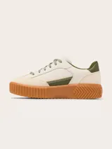 Zapatillas Sorel modelo Ona Ave T-Toe con diseño retro y plataforma. Presentan una combinación de cuero y gamuza en tonos crema, con detalles en verde oliva y suela de caucho color caramelo con textura estriada.