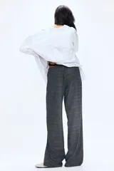 Pantalón holgado de pierna recta y tiro medio, confeccionado en tejido a cuadros gris. Presenta cintura elástica con cordón ajustable y bolsillos laterales.