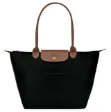 Bolso tipo shopper plegable, color negro, con asas y solapa de cuero color marrón claro. Presenta cierre principal con cremallera y un bolsillo exterior frontal.